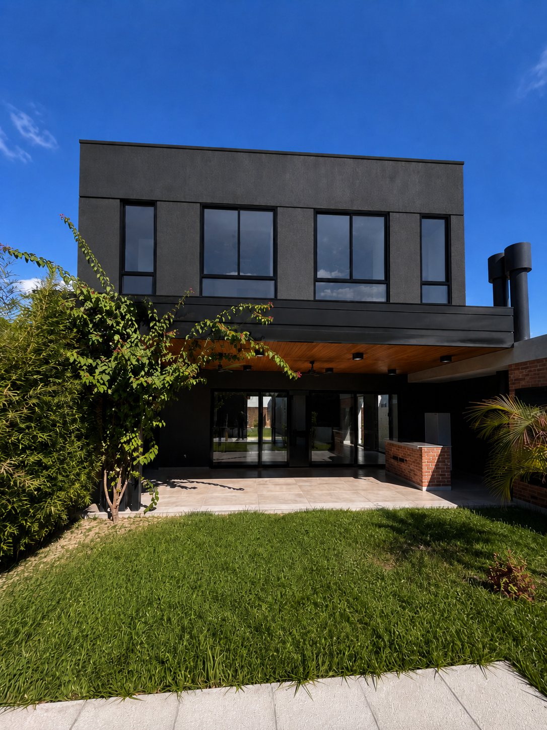 Fachada posterior de la Casa A&M con pérgola y jardín